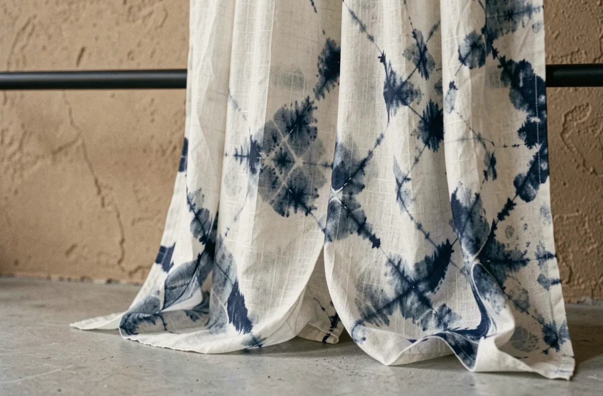 Détail de rideau en soie japonisant avec motif shibori indigo sur mur texturé sable